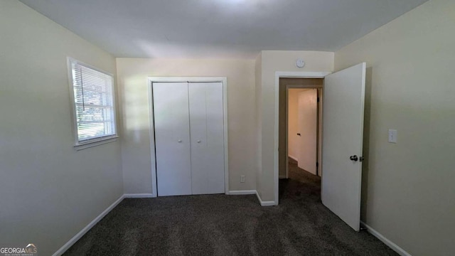 unfurnished bedroom with a closet and dark colored carpet