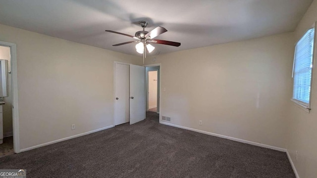 unfurnished bedroom with ceiling fan and dark carpet