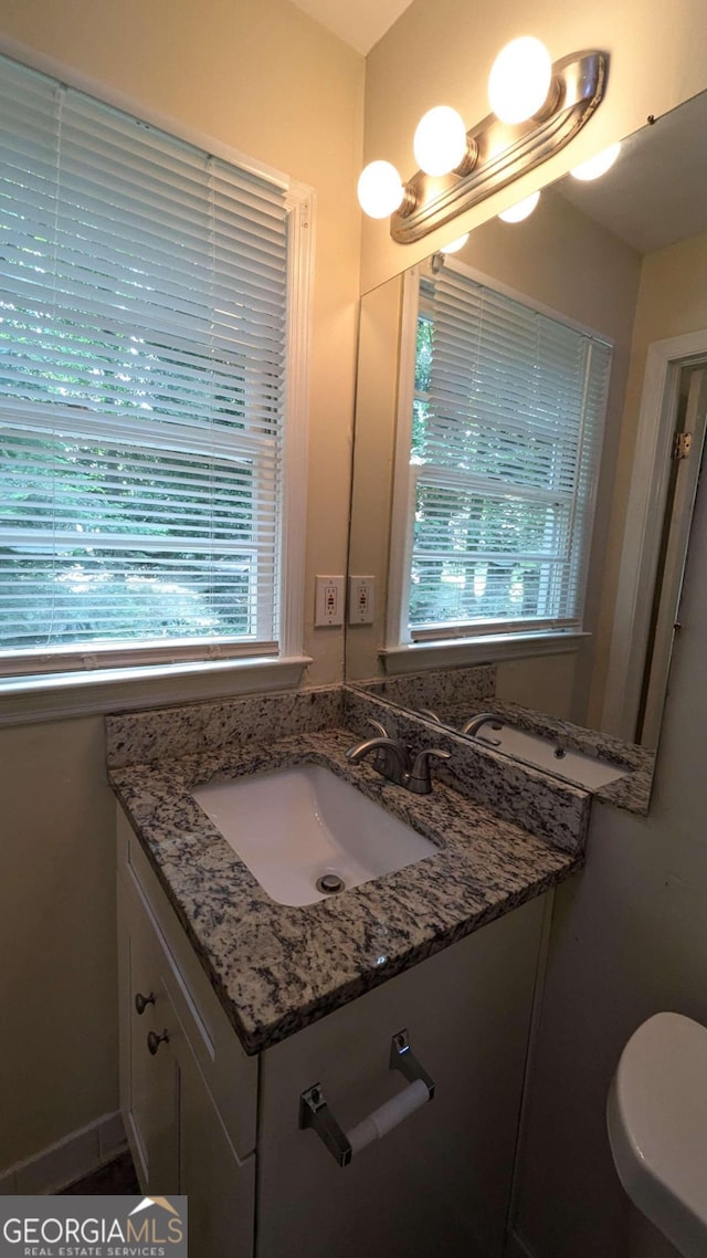 bathroom featuring a wealth of natural light, toilet, and vanity