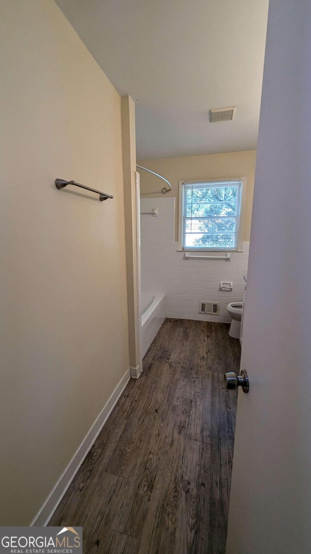 bathroom with tile walls, wood-type flooring, and toilet