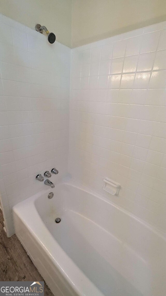 bathroom with hardwood / wood-style floors and tiled shower / bath combo