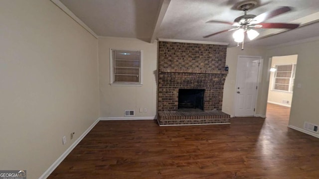 unfurnished living room with ceiling fan, a brick fireplace, dark wood-type flooring, and brick wall