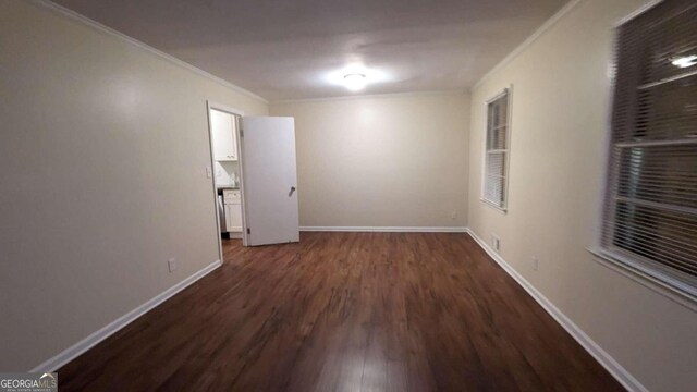 empty room with dark hardwood / wood-style flooring and ornamental molding