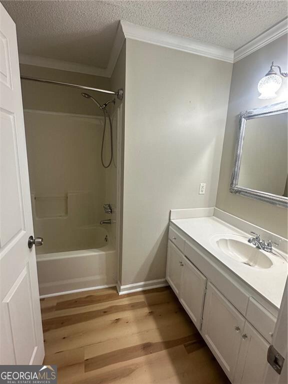 bathroom with shower / bath combination, hardwood / wood-style flooring, a textured ceiling, crown molding, and vanity