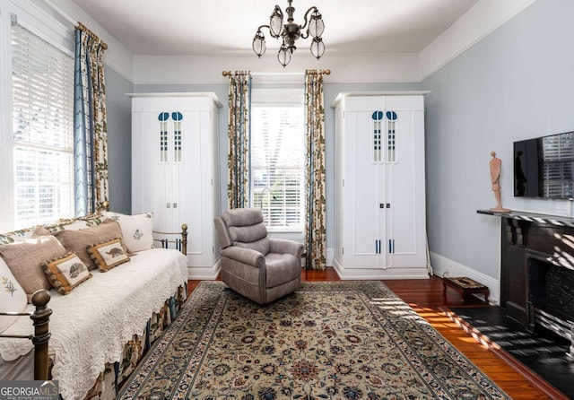 sitting room featuring an inviting chandelier, a healthy amount of sunlight, and dark hardwood / wood-style flooring