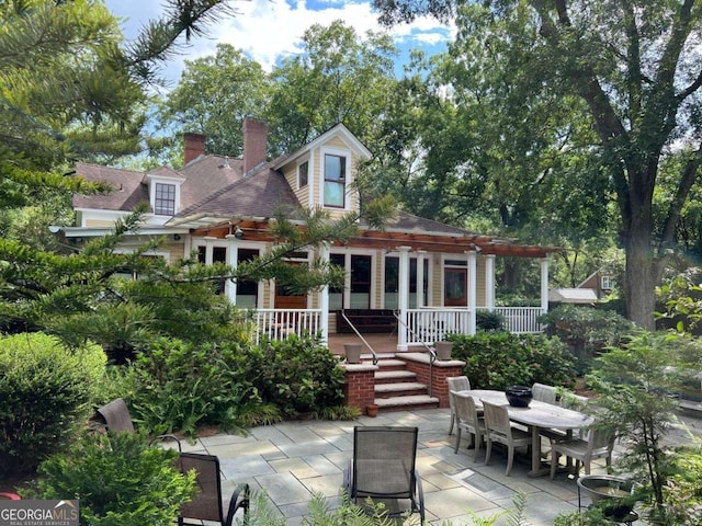 back of house with a wooden deck and a patio