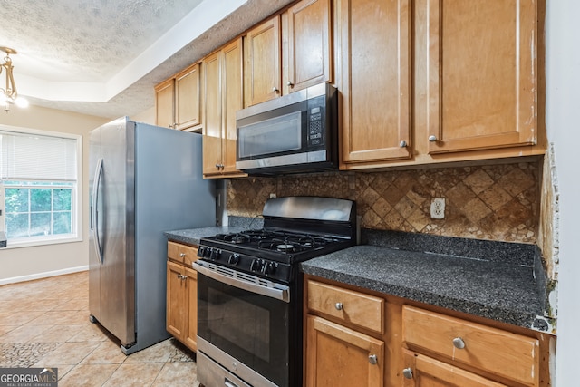 kitchen with dark stone counters, tasteful backsplash, a textured ceiling, light tile patterned floors, and stainless steel appliances