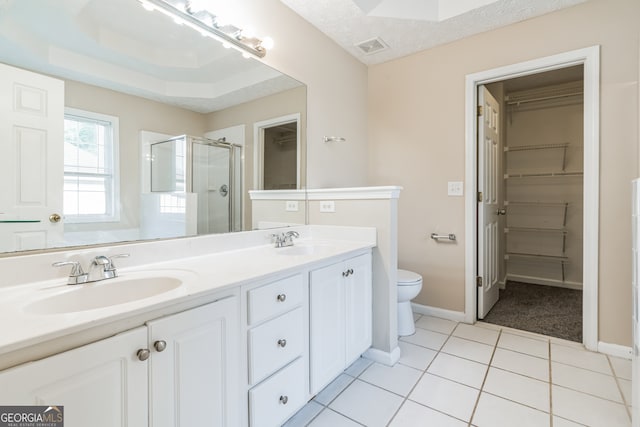 bathroom featuring double sink vanity, tile patterned floors, a raised ceiling, toilet, and a shower with door