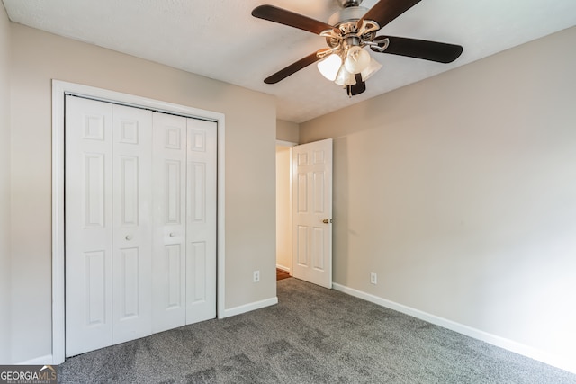 unfurnished bedroom featuring dark colored carpet, ceiling fan, and a closet