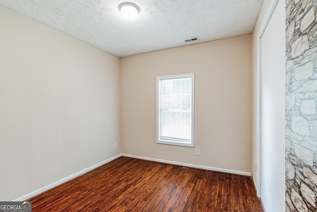 empty room with a textured ceiling and hardwood / wood-style floors