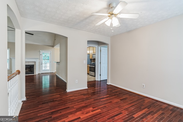 unfurnished room featuring ceiling fan, wood-type flooring, a textured ceiling, and a fireplace