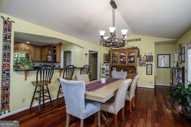 dining room with a notable chandelier, dark wood-type flooring, and lofted ceiling