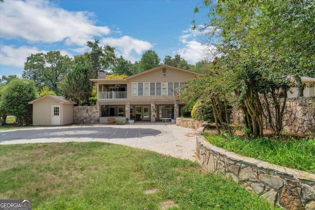 view of front of property featuring a storage unit and a front lawn