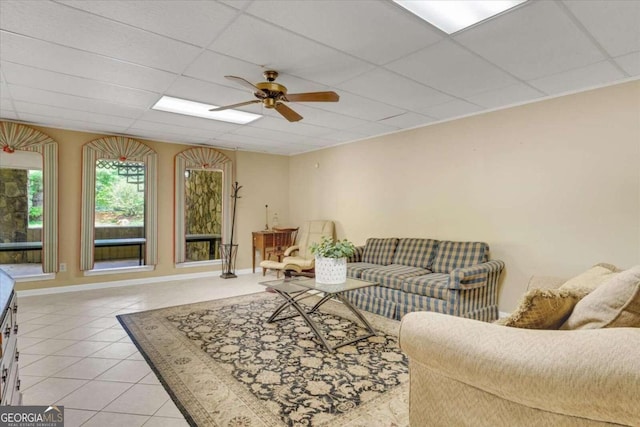 tiled living room with ceiling fan and a paneled ceiling