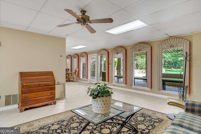 interior space featuring a paneled ceiling, ceiling fan, and light tile patterned floors