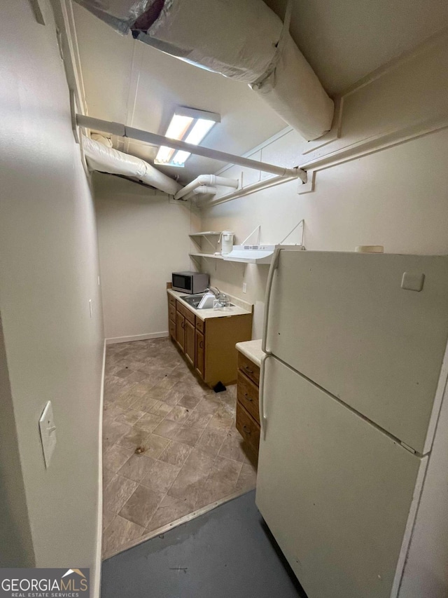 basement with light tile patterned floors and white fridge