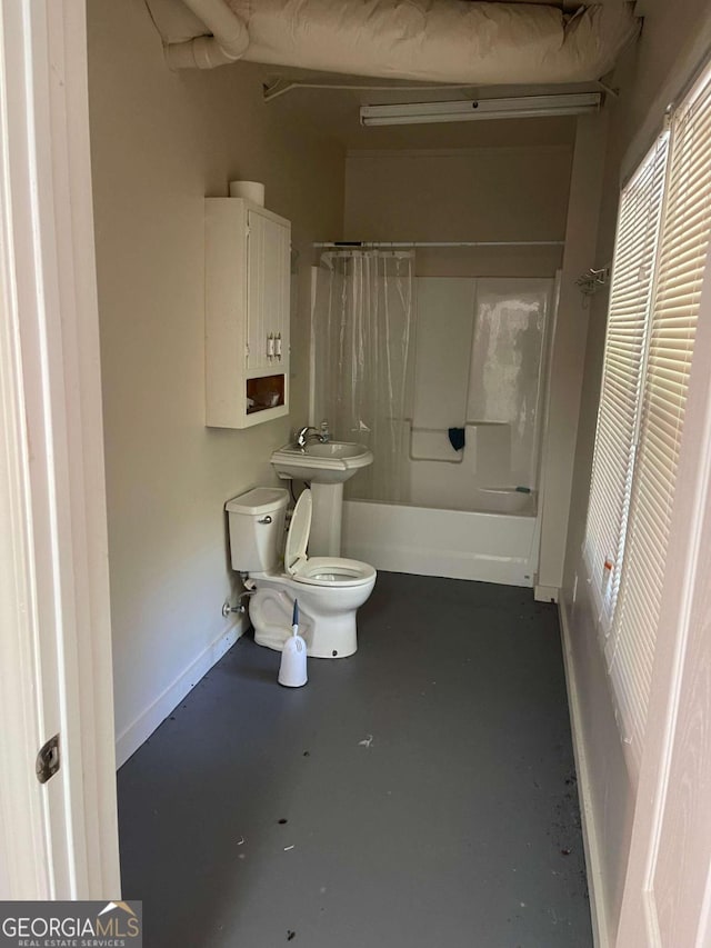 bathroom with shower / bath combo, concrete floors, and toilet