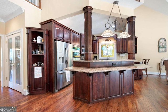 kitchen with pendant lighting, stainless steel refrigerator with ice dispenser, dark hardwood / wood-style flooring, light stone countertops, and sink