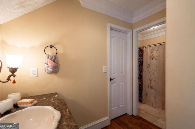 bathroom featuring hardwood / wood-style floors, ornamental molding, and a textured ceiling