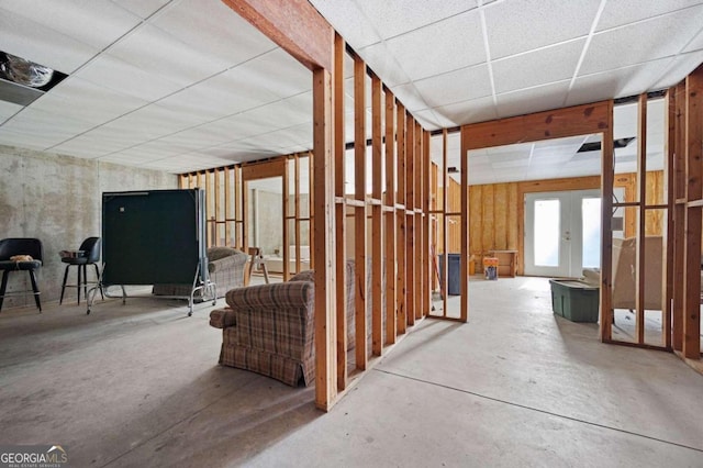 interior space featuring a drop ceiling, concrete floors, and french doors