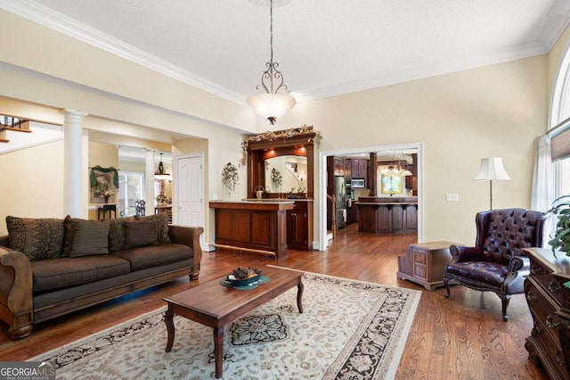 living room with crown molding, decorative columns, and dark wood-type flooring