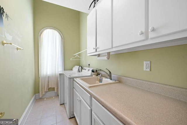 laundry area with sink, washing machine and dryer, light tile patterned floors, and cabinets