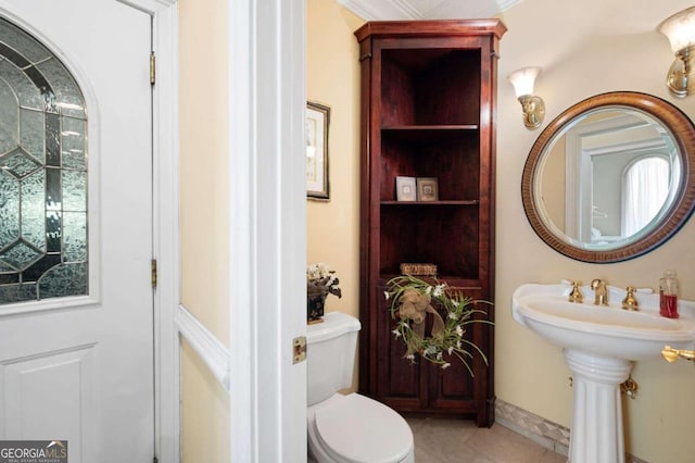 bathroom with toilet, crown molding, and tile patterned floors