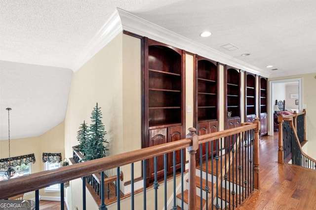 hall with a textured ceiling, vaulted ceiling, ornamental molding, and wood-type flooring