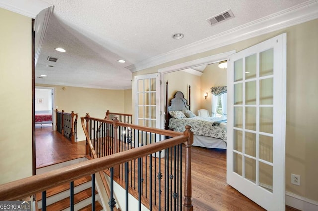 hallway featuring hardwood / wood-style flooring, a textured ceiling, and ornamental molding