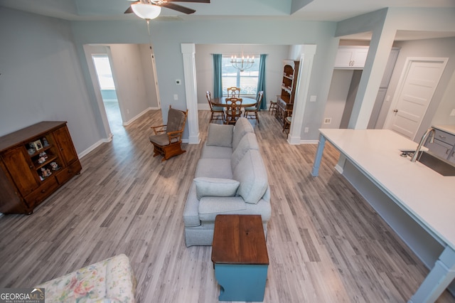 living room featuring light hardwood / wood-style floors and ceiling fan with notable chandelier