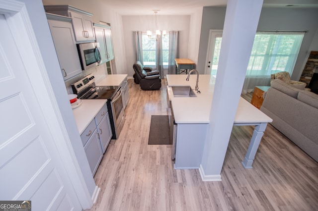 kitchen with appliances with stainless steel finishes, light hardwood / wood-style flooring, decorative light fixtures, sink, and gray cabinetry