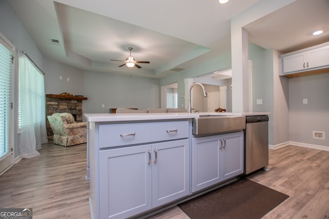 kitchen featuring ceiling fan, light wood-type flooring, a raised ceiling, dishwasher, and a wealth of natural light