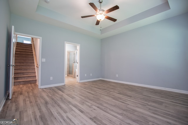 unfurnished bedroom featuring a raised ceiling, wood-type flooring, and ensuite bathroom