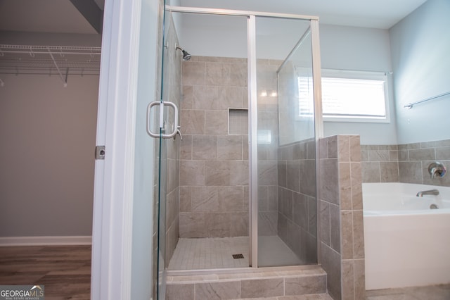 bathroom with wood-type flooring and shower with separate bathtub