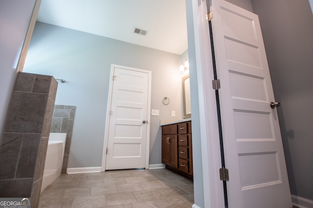 bathroom featuring tile patterned flooring, a bathtub, and vanity