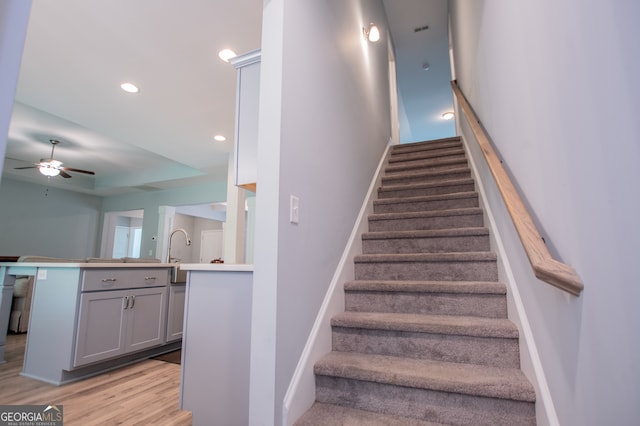 staircase featuring ceiling fan and hardwood / wood-style floors