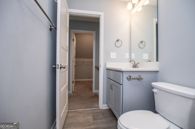 bathroom with toilet, hardwood / wood-style flooring, and vanity