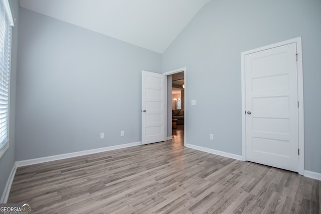 unfurnished bedroom featuring light wood-type flooring and high vaulted ceiling