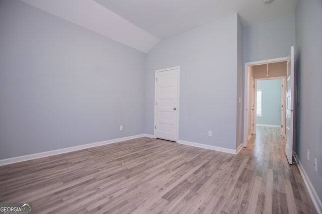 unfurnished bedroom with high vaulted ceiling and light hardwood / wood-style flooring