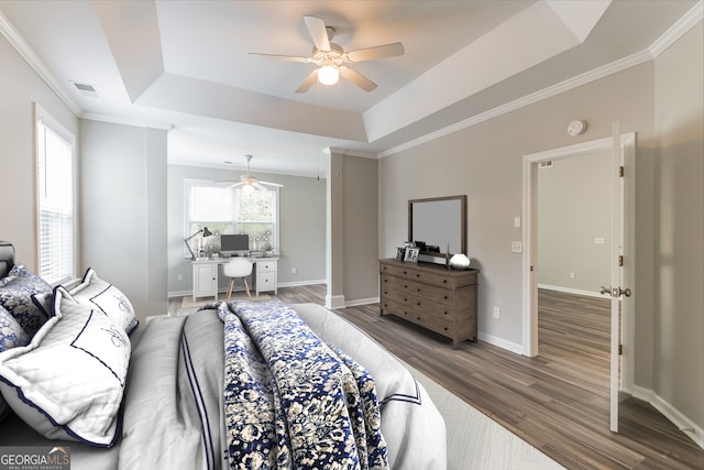 bedroom featuring ceiling fan, a raised ceiling, hardwood / wood-style floors, and ornamental molding