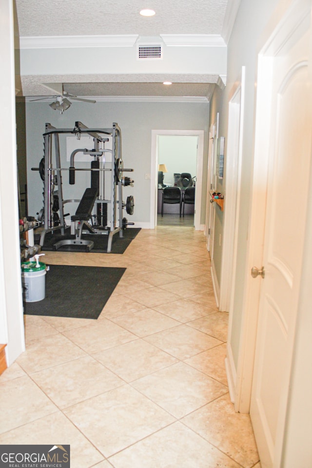 exercise room with ceiling fan, light tile patterned floors, a textured ceiling, and ornamental molding