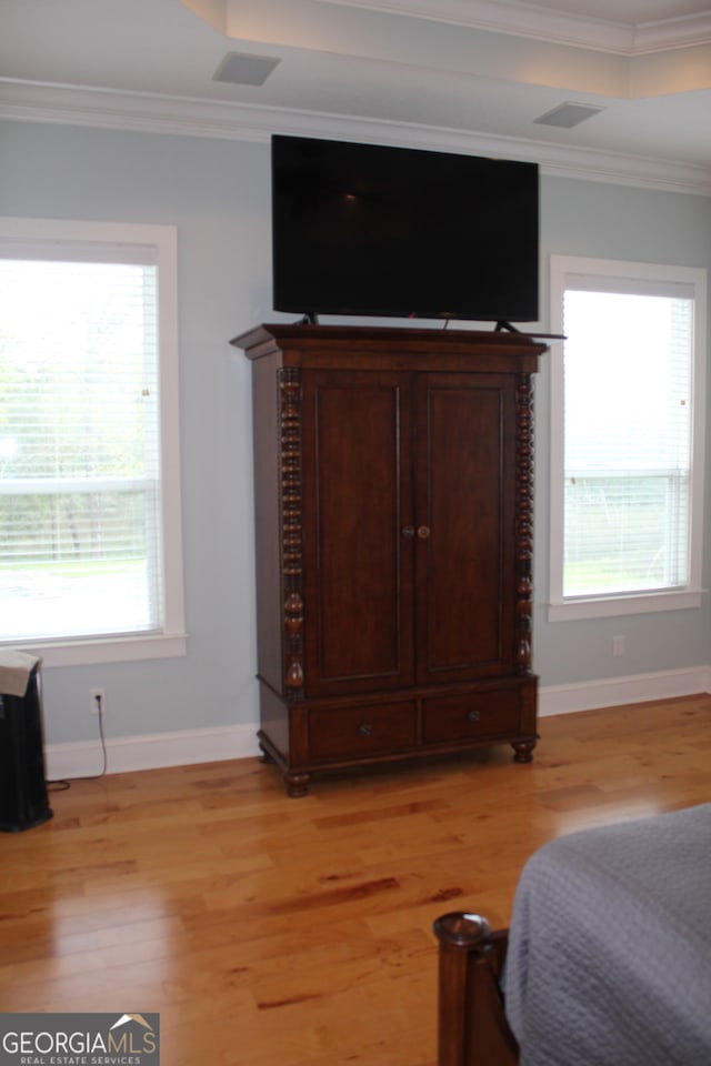 bedroom featuring light wood-type flooring, multiple windows, and crown molding