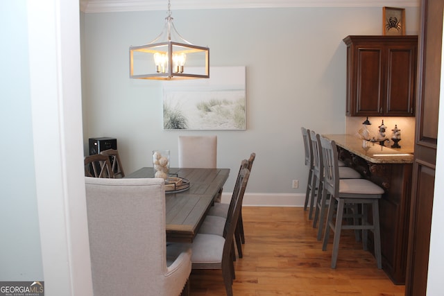 dining area with crown molding, light hardwood / wood-style floors, and an inviting chandelier