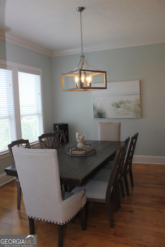 dining space with a notable chandelier, a textured ceiling, hardwood / wood-style flooring, and crown molding