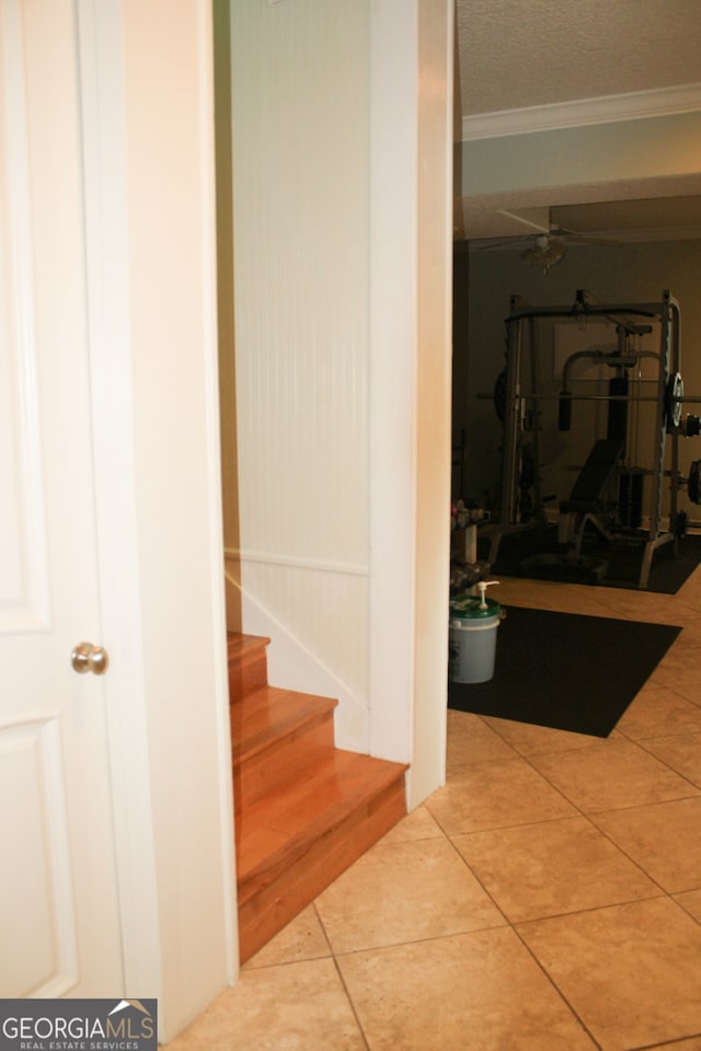 stairs with ornamental molding, a textured ceiling, and tile patterned floors