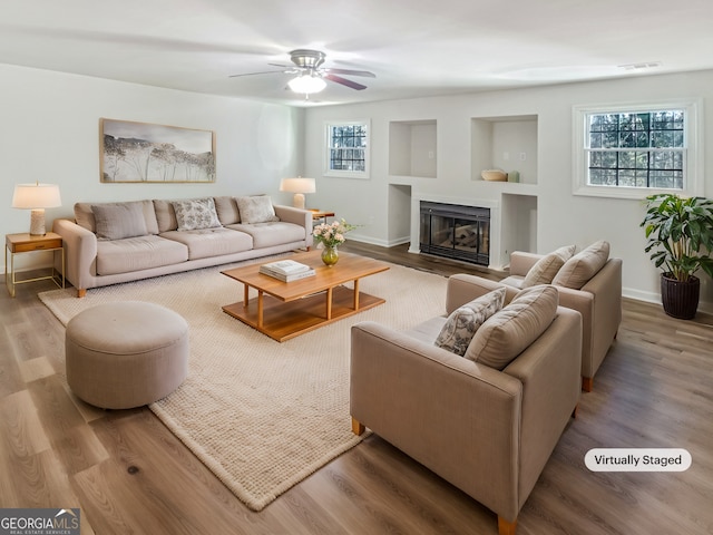 living room featuring ceiling fan, wood-type flooring, and a healthy amount of sunlight