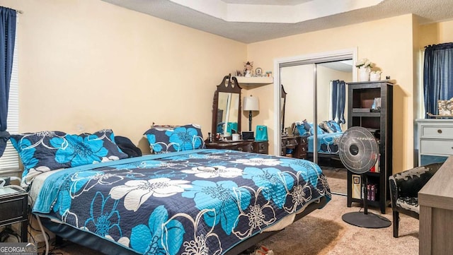 carpeted bedroom with a closet and a raised ceiling