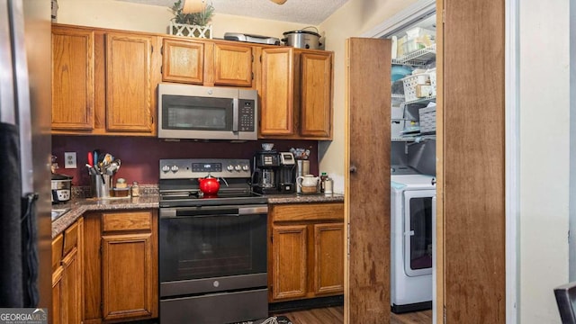 kitchen with dark hardwood / wood-style floors, stainless steel appliances, and washer / dryer