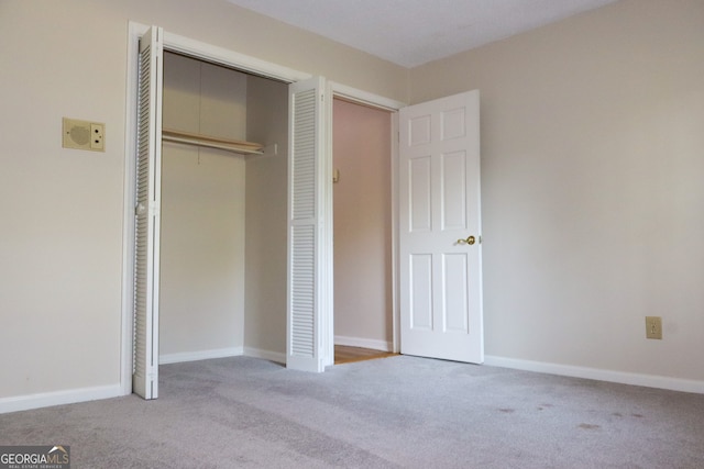 unfurnished bedroom featuring light carpet and a closet