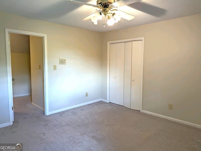 unfurnished bedroom featuring ceiling fan, a textured ceiling, a closet, and light carpet